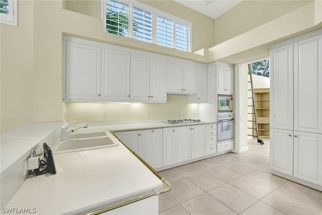 kitchen featuring stainless steel gas cooktop, built in microwave, sink, oven, and white cabinetry