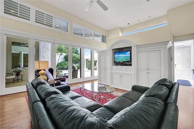 living room with french doors, light hardwood / wood-style flooring, ceiling fan, and a high ceiling