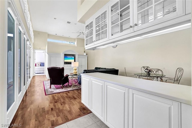 kitchen with white cabinets, ceiling fan, light tile patterned flooring, and a high ceiling