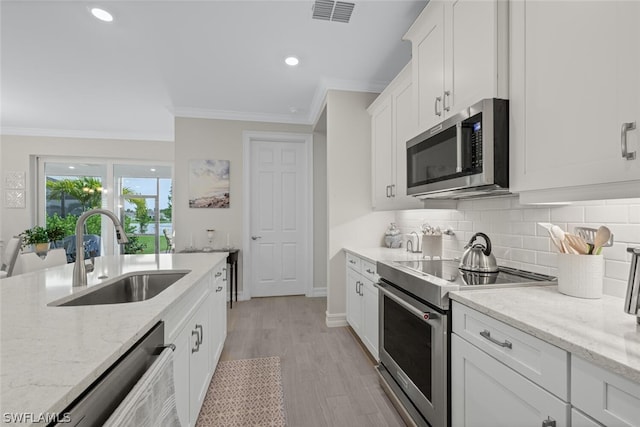 kitchen featuring stainless steel appliances, white cabinetry, sink, and light stone countertops