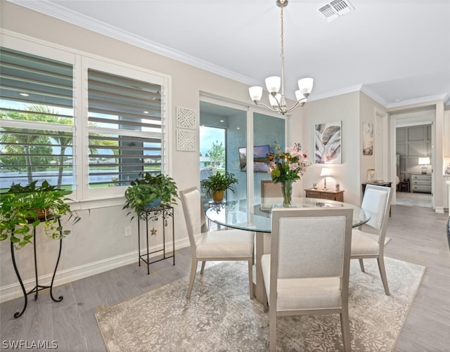 dining space with light hardwood / wood-style floors, ornamental molding, and a chandelier