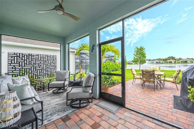 sunroom / solarium featuring ceiling fan and a water view