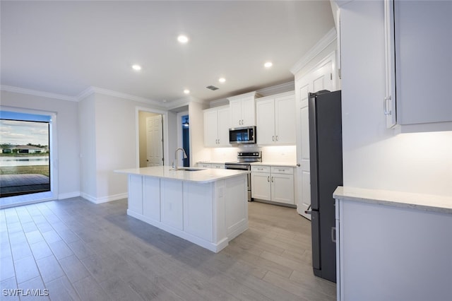 kitchen with an island with sink, sink, white cabinets, light hardwood / wood-style floors, and stainless steel appliances