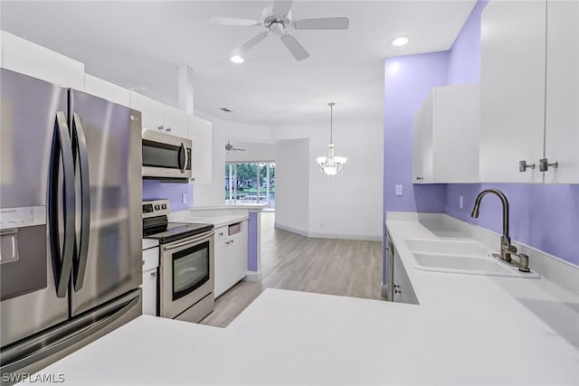 kitchen with ceiling fan with notable chandelier, sink, decorative light fixtures, white cabinetry, and stainless steel appliances