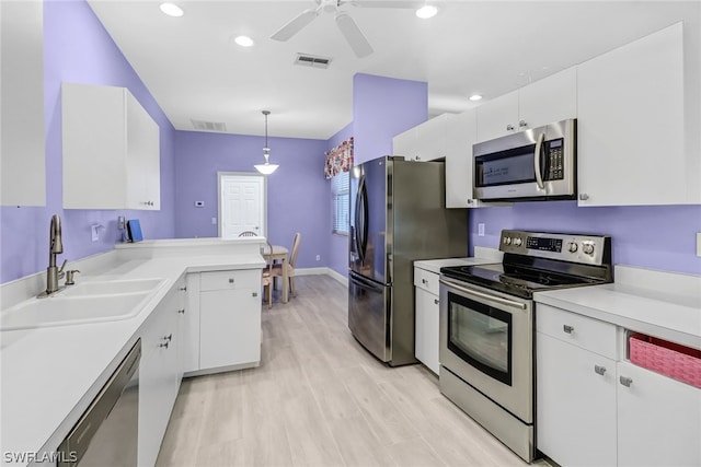 kitchen with white cabinets, appliances with stainless steel finishes, and pendant lighting