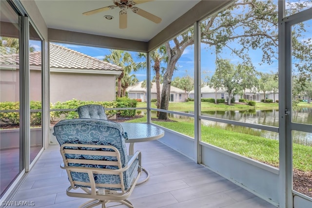 sunroom featuring a water view, ceiling fan, and a healthy amount of sunlight