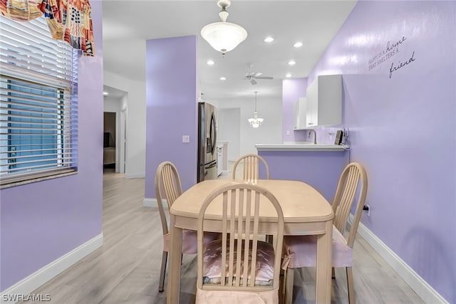 dining space featuring ceiling fan with notable chandelier and light wood-type flooring