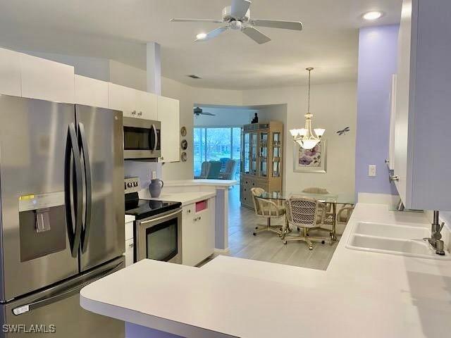 kitchen with white cabinets, sink, hanging light fixtures, and appliances with stainless steel finishes