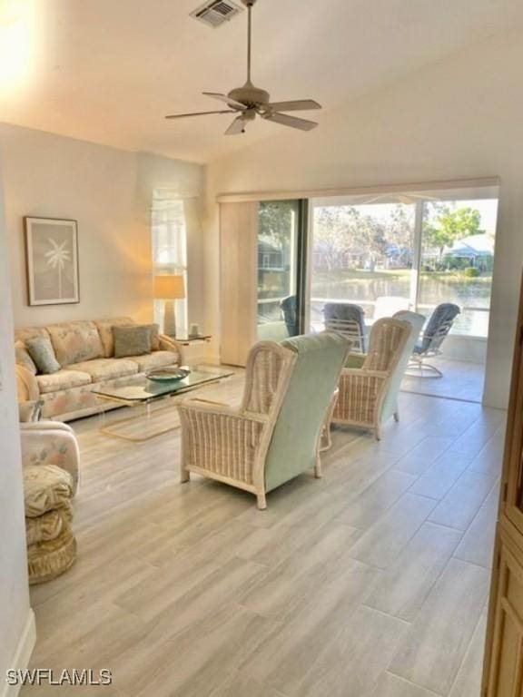 living room with light hardwood / wood-style floors, vaulted ceiling, and ceiling fan