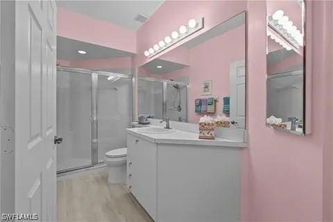 bathroom featuring vanity, hardwood / wood-style flooring, toilet, and a shower with shower door