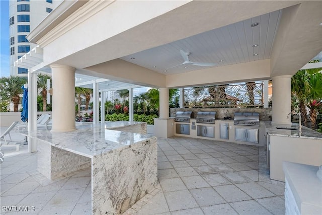 view of patio / terrace featuring ceiling fan, area for grilling, and exterior kitchen