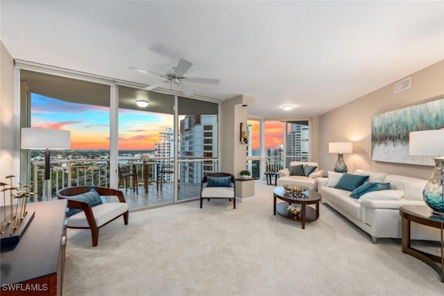 carpeted living room with ceiling fan, expansive windows, and a wealth of natural light