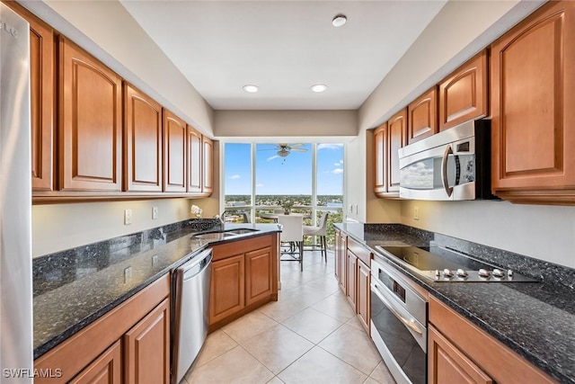 kitchen featuring light tile patterned floors, appliances with stainless steel finishes, sink, and dark stone countertops