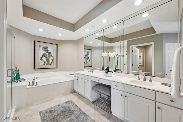 bathroom with a tub, vanity, a raised ceiling, and tile patterned flooring