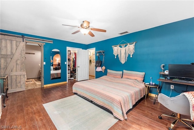 bedroom featuring a barn door, wood-type flooring, a spacious closet, and a closet