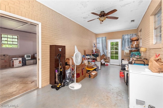 miscellaneous room featuring ceiling fan and brick wall