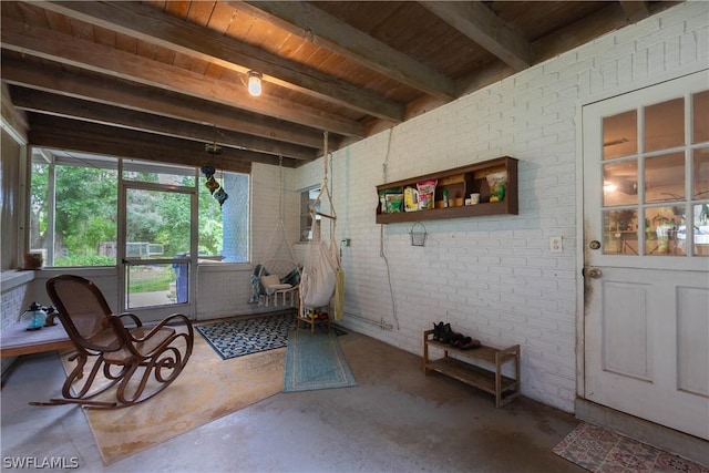 living area with wood ceiling, concrete flooring, beamed ceiling, and brick wall