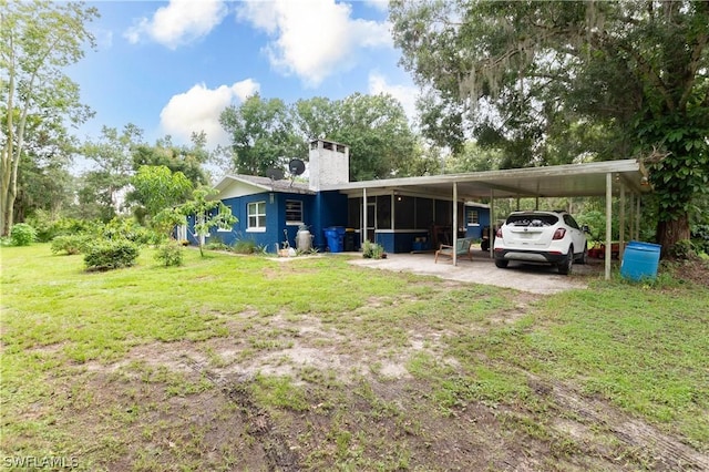 exterior space featuring a carport, a sunroom, and a front yard