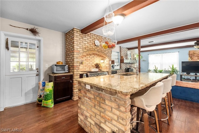 kitchen with dark wood-type flooring, sink, decorative light fixtures, a kitchen breakfast bar, and beamed ceiling