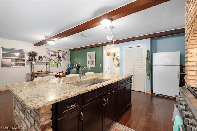 kitchen featuring sink, a kitchen island with sink, stainless steel range oven, decorative light fixtures, and white fridge