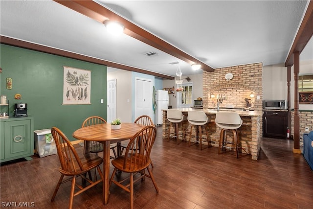 dining area with beam ceiling and dark hardwood / wood-style flooring