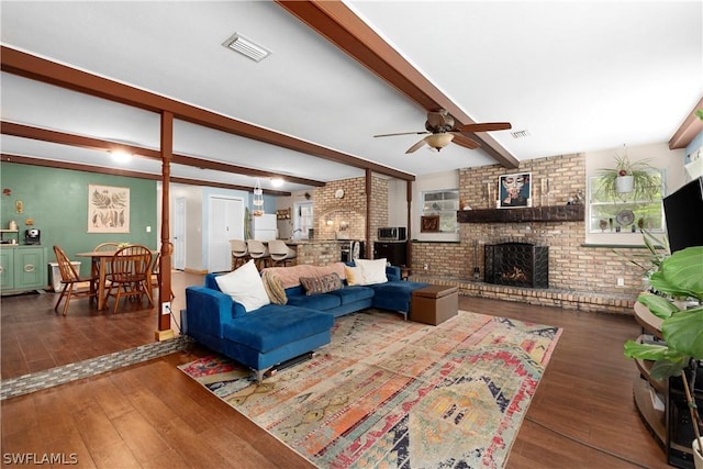 living room with brick wall, wood-type flooring, ceiling fan, a brick fireplace, and beam ceiling