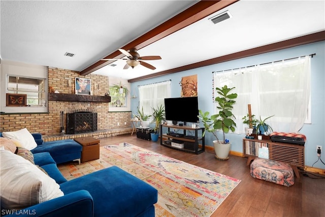 living room featuring a brick fireplace, beam ceiling, a wealth of natural light, and hardwood / wood-style floors