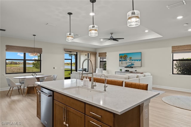 kitchen with dishwasher, a tray ceiling, open floor plan, and a sink