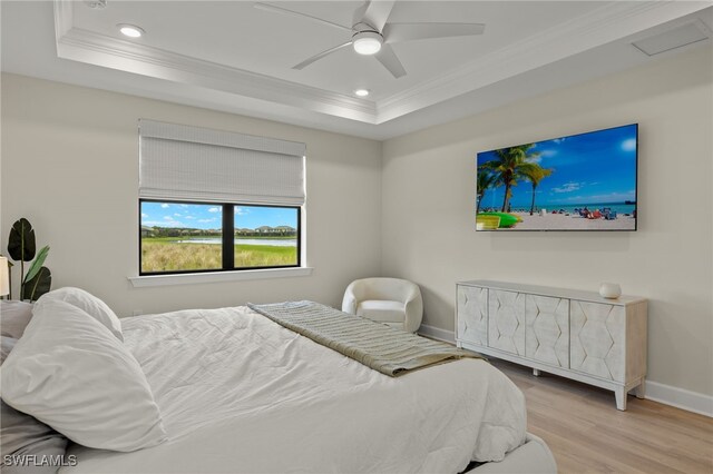 bedroom featuring a tray ceiling, recessed lighting, ornamental molding, light wood-style floors, and baseboards