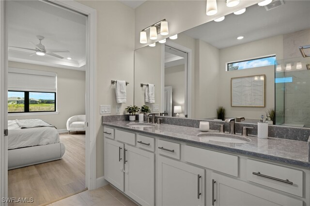 bathroom featuring tiled shower, a sink, visible vents, and connected bathroom