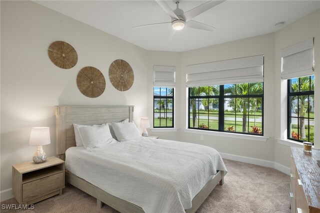 bedroom featuring a ceiling fan, carpet, multiple windows, and baseboards