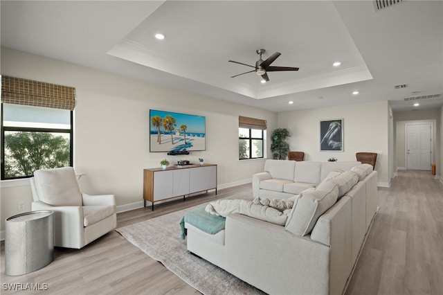 living room with light wood finished floors, baseboards, a tray ceiling, and recessed lighting