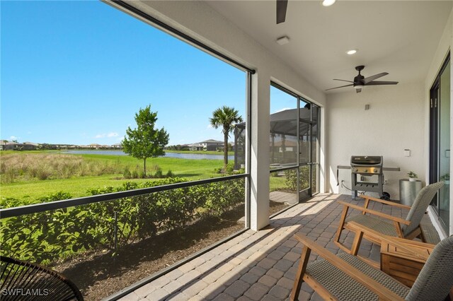 sunroom featuring a water view and ceiling fan