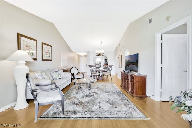 living room featuring vaulted ceiling, light wood-type flooring, and a chandelier