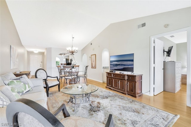 living room featuring light wood-type flooring, lofted ceiling, and a notable chandelier