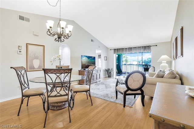 dining area featuring high vaulted ceiling, light hardwood / wood-style flooring, and an inviting chandelier