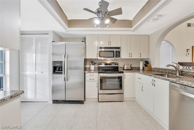 kitchen with light stone counters, sink, stainless steel appliances, and a tray ceiling