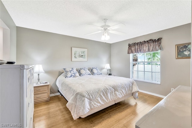 bedroom with a textured ceiling, light hardwood / wood-style floors, and ceiling fan