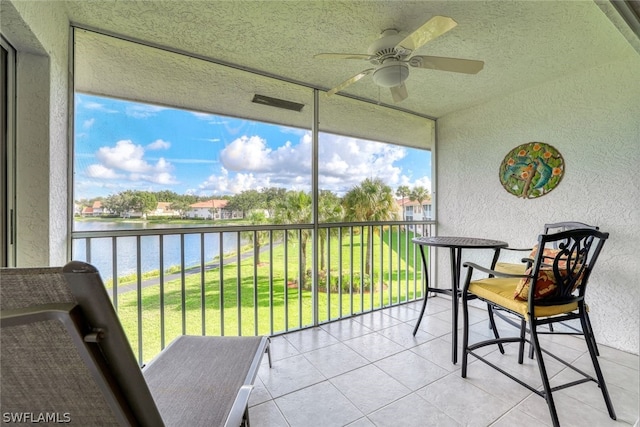 sunroom / solarium featuring ceiling fan and a water view