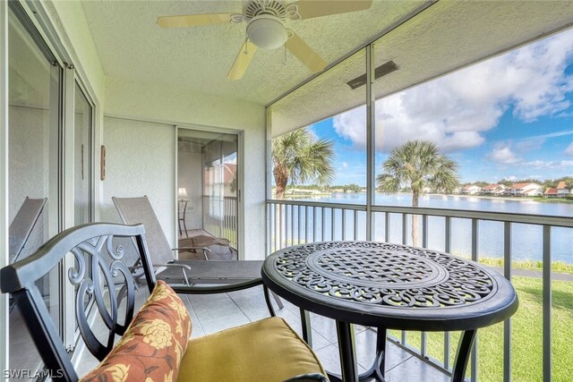 sunroom with a water view and ceiling fan