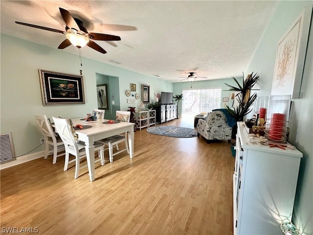 dining area with a textured ceiling, ceiling fan, and light hardwood / wood-style floors