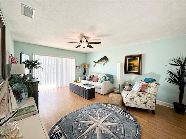 living room with ceiling fan, a textured ceiling, and hardwood / wood-style flooring