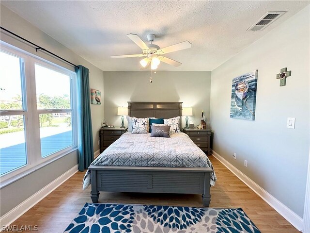 bedroom featuring a textured ceiling, ceiling fan, and wood-type flooring