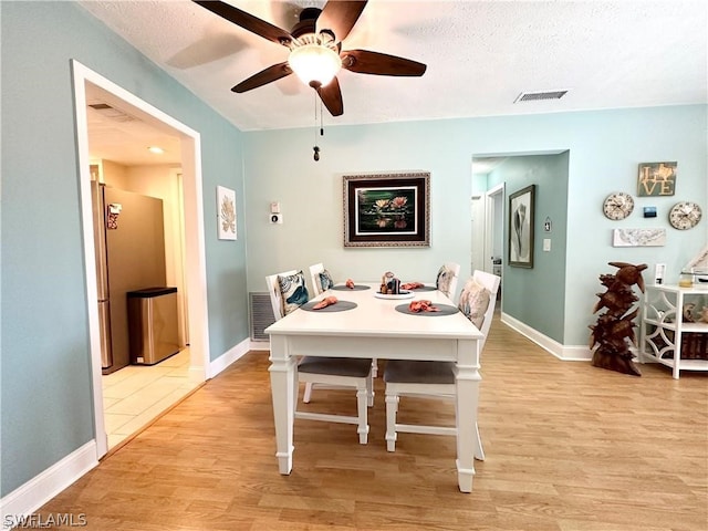 dining space with a textured ceiling, light wood-type flooring, and ceiling fan