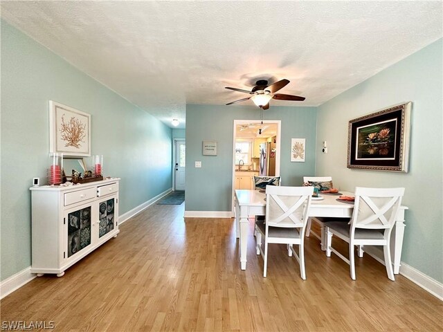 dining area with ceiling fan, a textured ceiling, and light hardwood / wood-style flooring