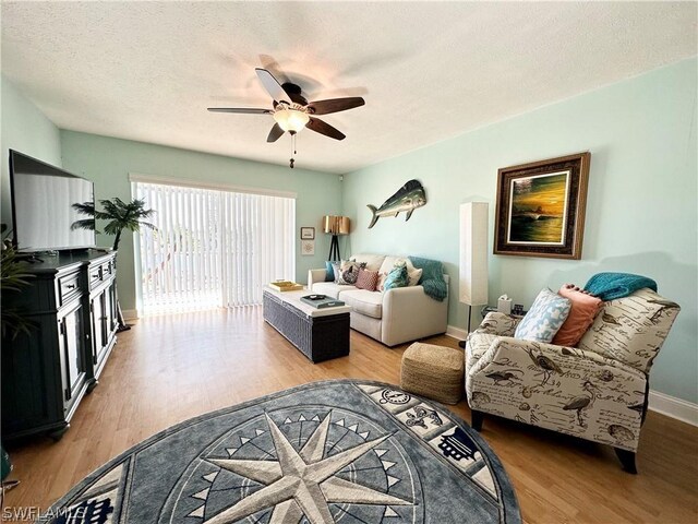 living room with a textured ceiling, wood-type flooring, and ceiling fan