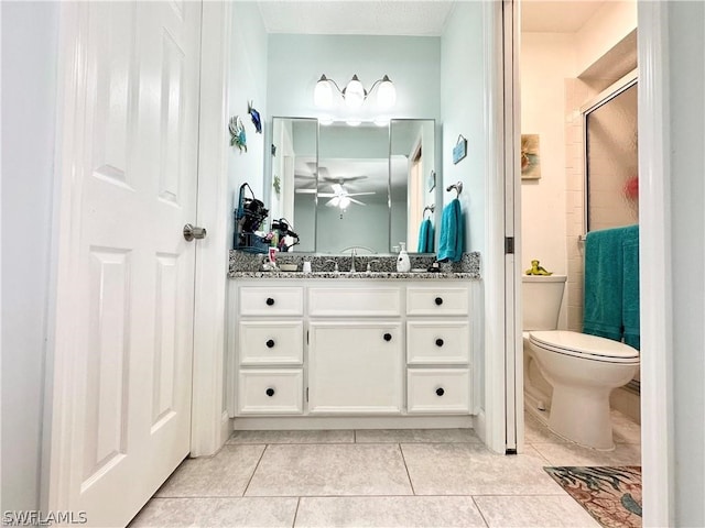 bathroom with tile patterned flooring, toilet, vanity, and ceiling fan