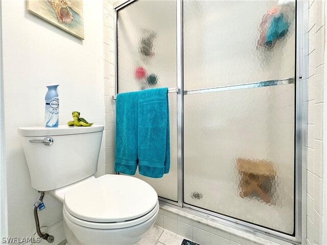 bathroom featuring a shower with shower door, tile patterned floors, and toilet