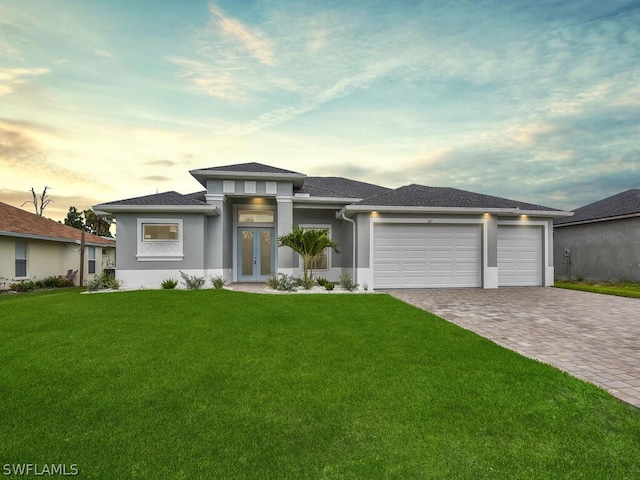 prairie-style house with a garage, a lawn, and french doors