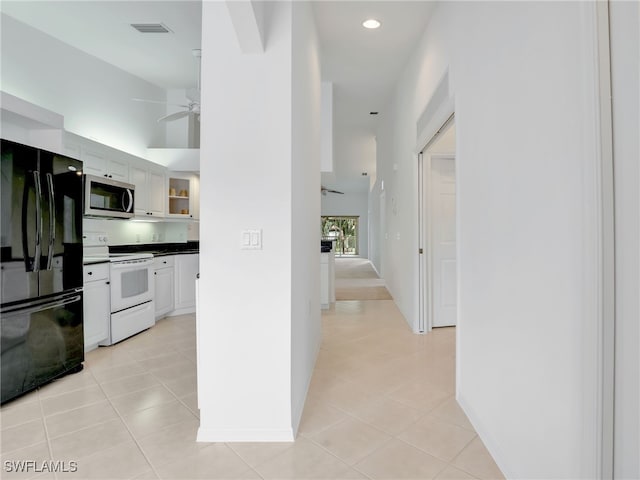 hall with light tile patterned flooring, recessed lighting, a high ceiling, visible vents, and baseboards